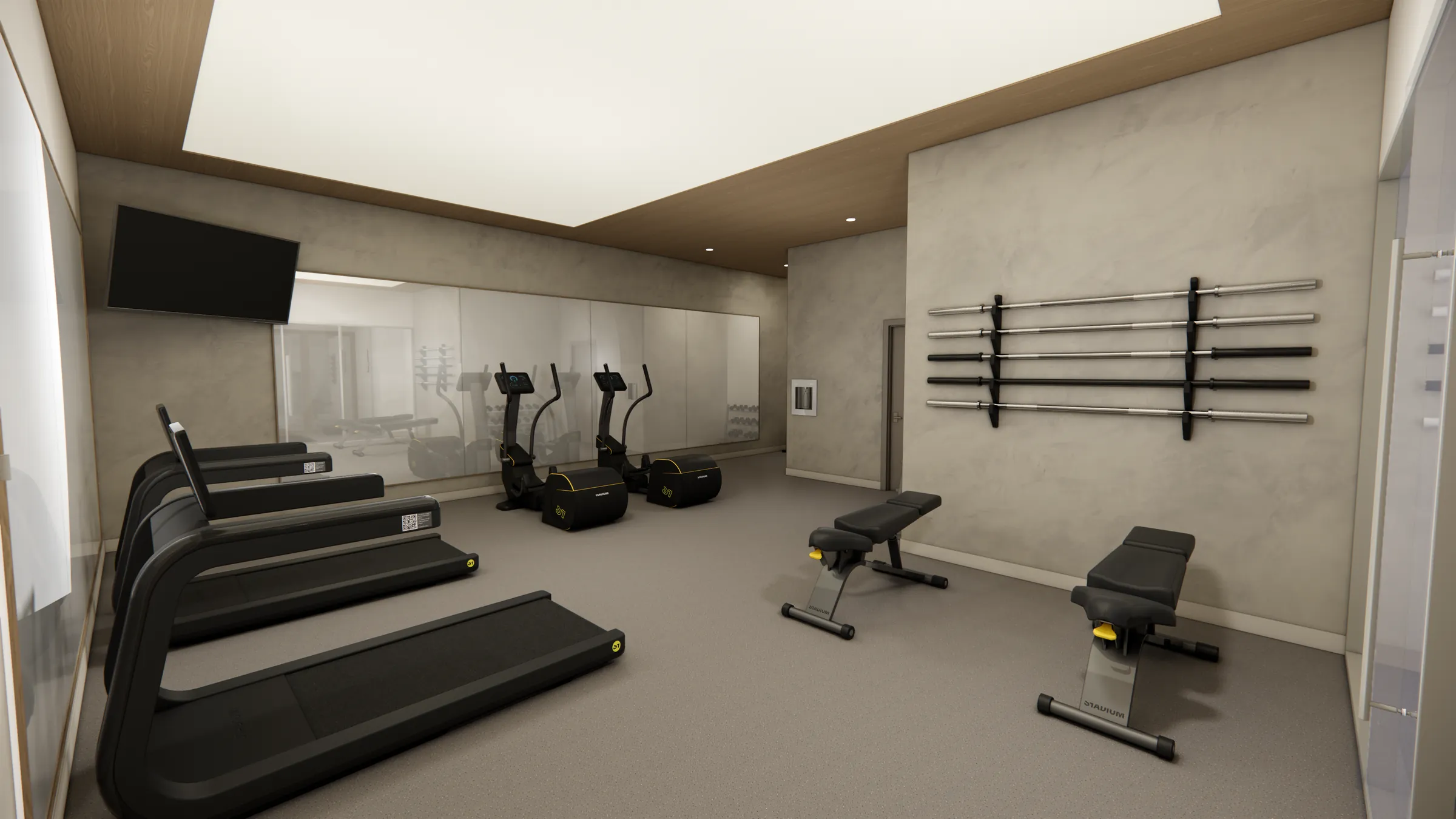 Fitness studio at Serenity Kelowna with treadmills, ellipticals, benches, and wall-mounted Olympic bars